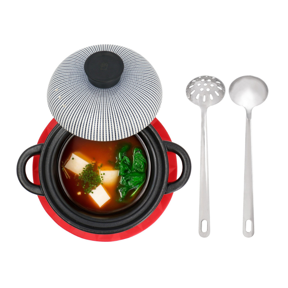 Small pot with soup and a lid, accompanied by two ladles on a white background